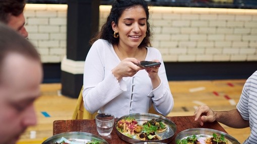 Girl taking a picture of her food at Mackie Mayor